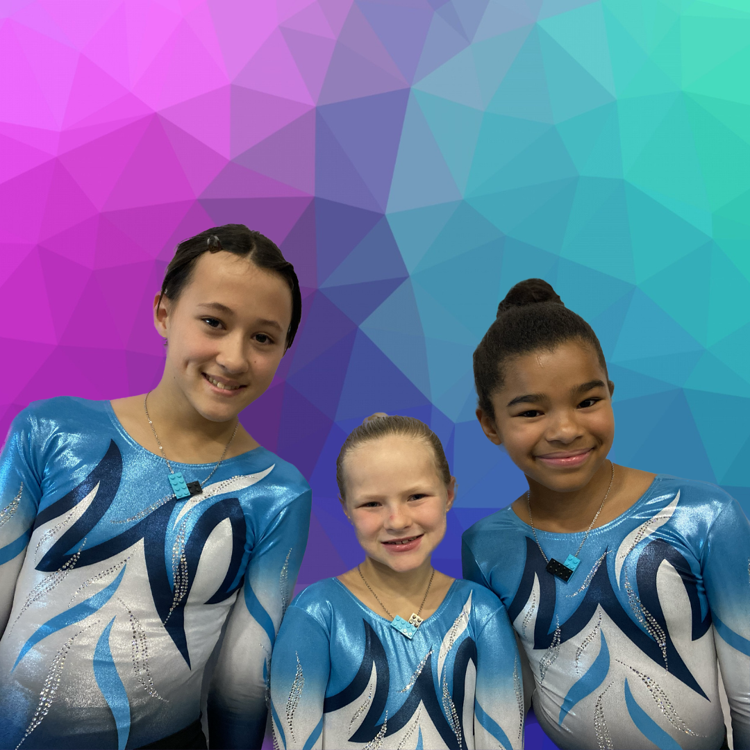 three gymnasts standing together in their team uniform wearing matching Tu Snaps necklaces made from Lego pieces