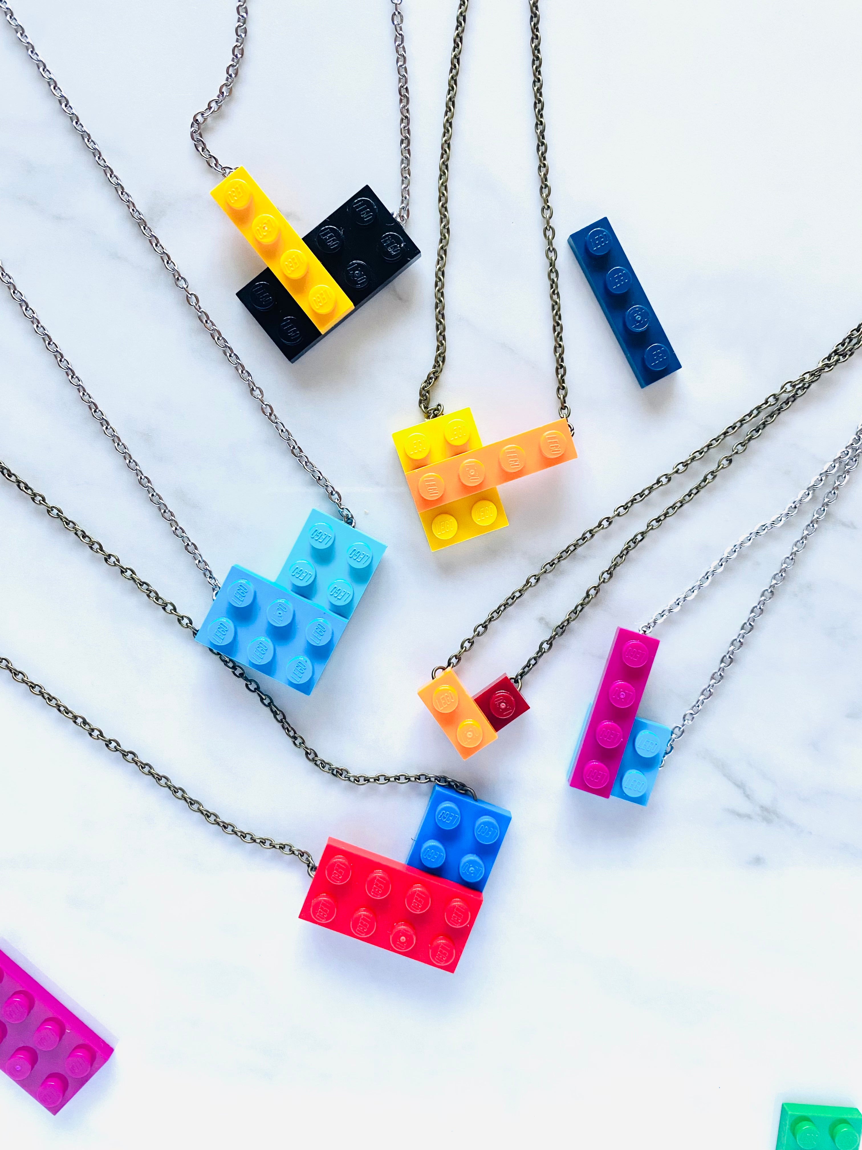 Several colors and shapes of Tu Snaps necklaces made from Lego pieces