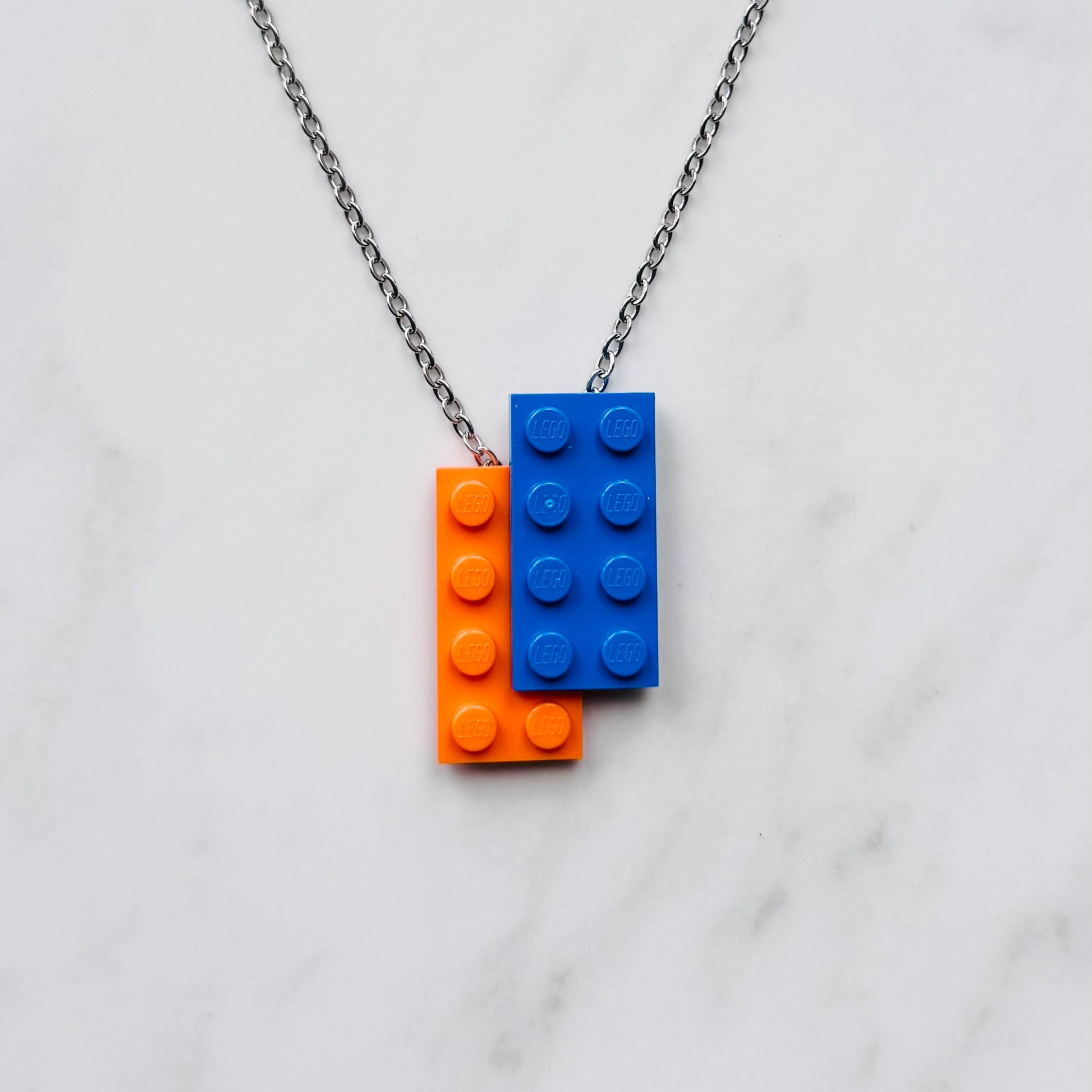 Necklace with orange and blue LEGO brick pendants on a marble background