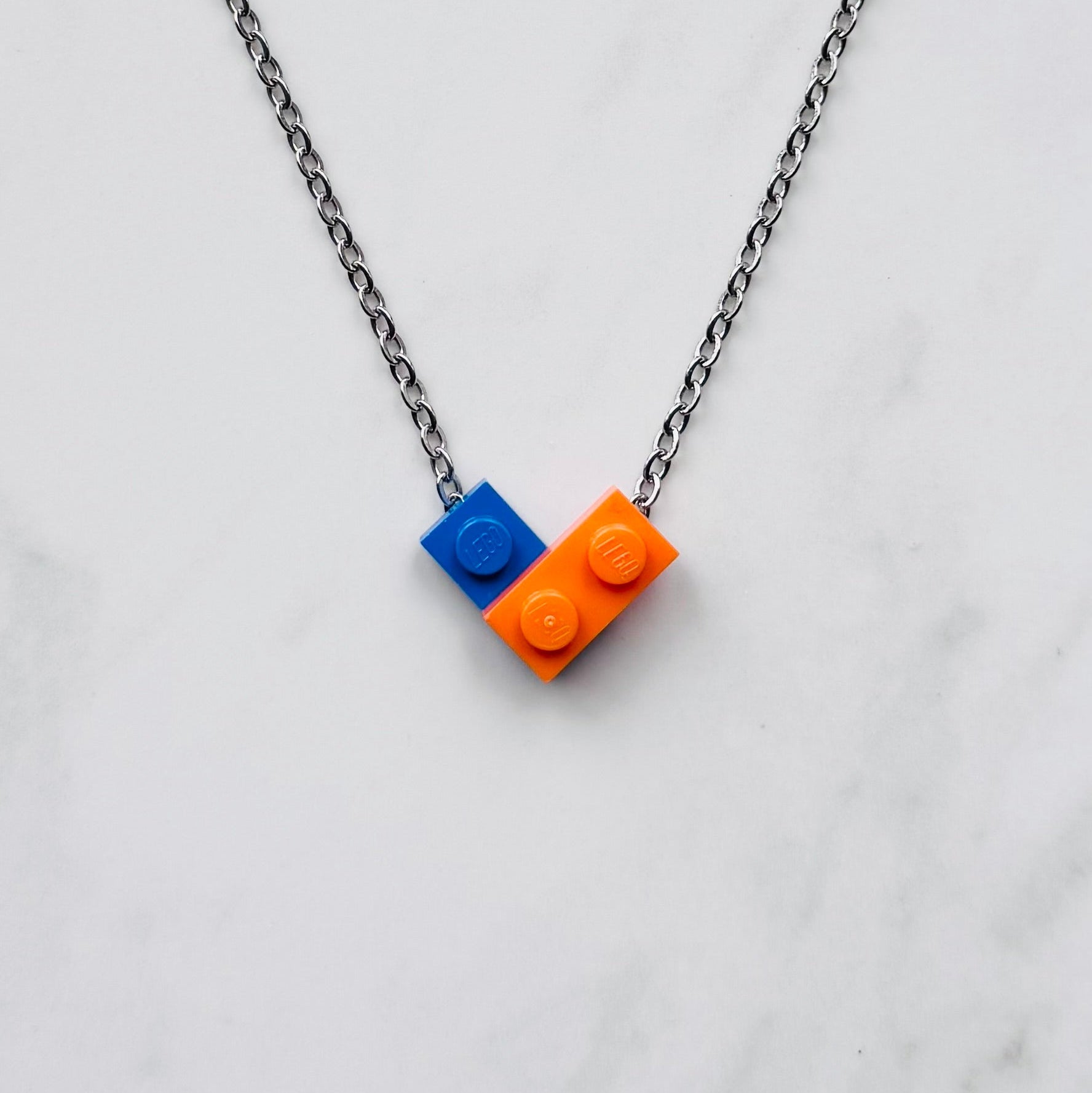 Necklace with blue and orange LEGO-style brick pendant on a light gray background