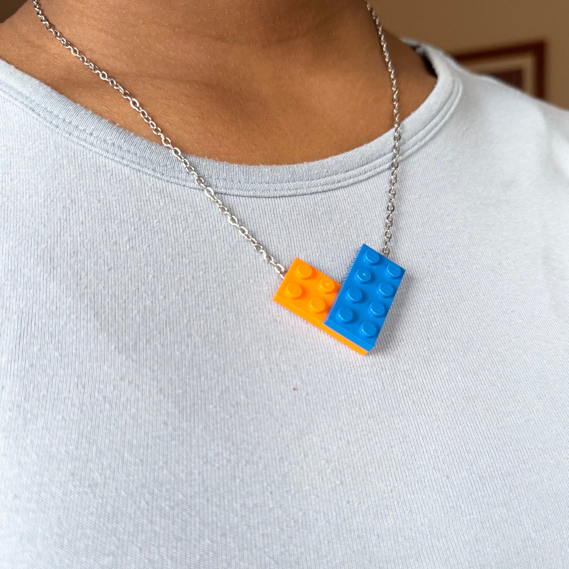 Necklace with orange and blue brick pendants on a person